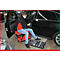 Un homme dans un atelier répare une voiture. Il est assis sur un tabouret rouge et a des boîtes à outils devant lui.